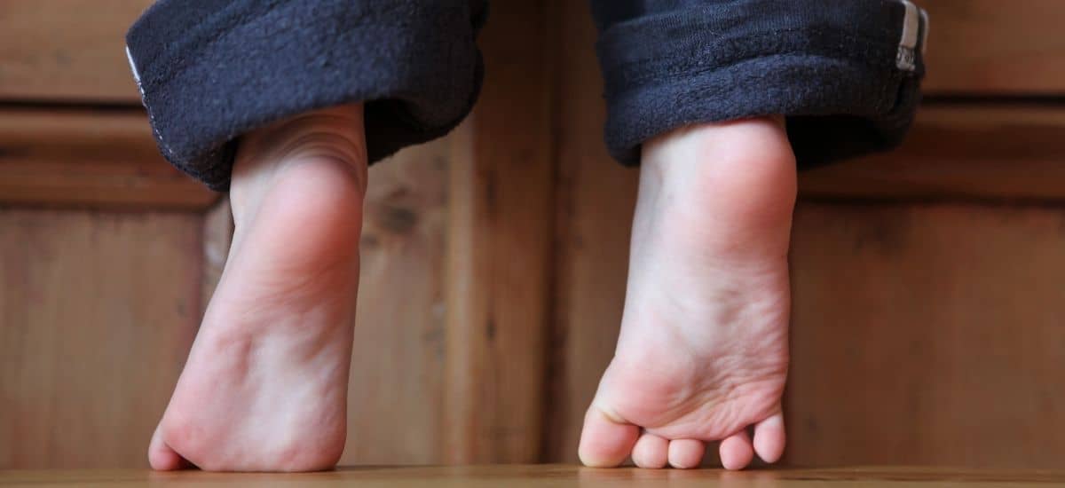 Barn som står på tå för att nå (reach)