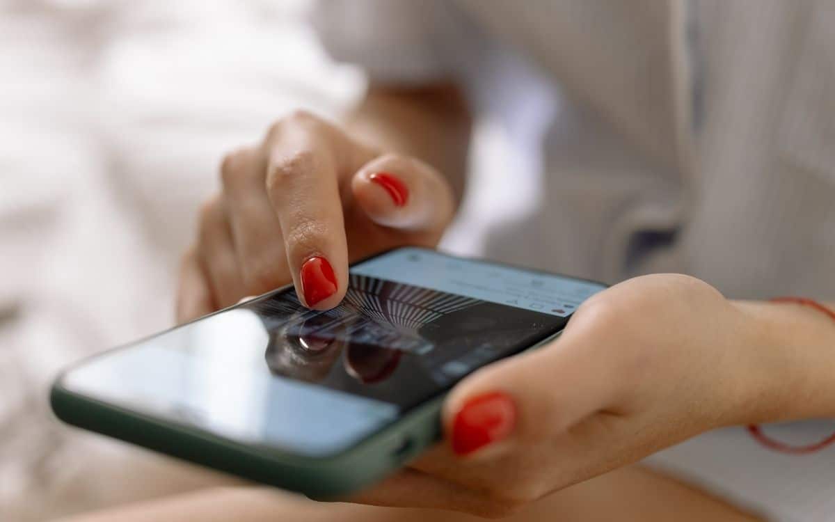 En hand som scrollar på en telefon, digitala nyheter om Instagram links i Stories.