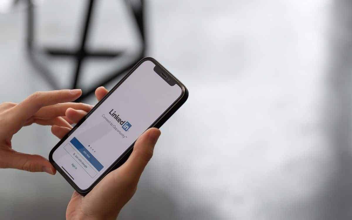 Händer håller en mobil som visar LinkedIns inloggningssida.