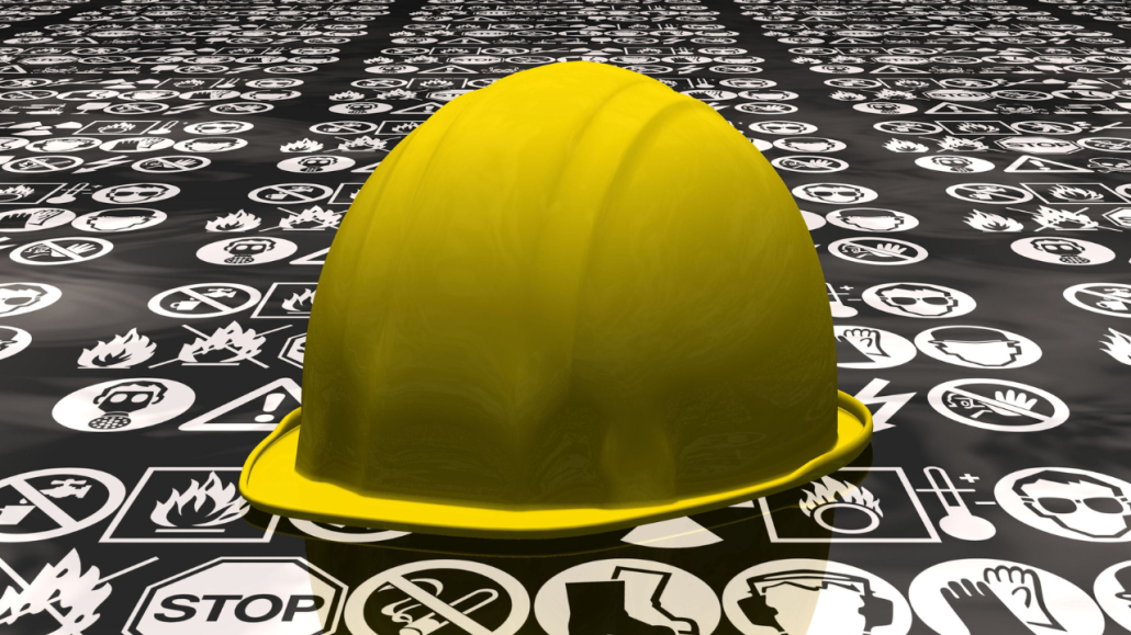 Gul hjälm liggande på olika varnings-symboler